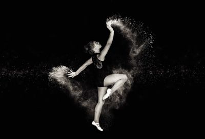 Full length of girl dancing against black background