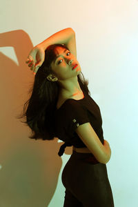 Close-up of young woman standing against gray background