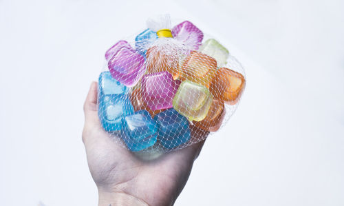 Close-up of hand holding ice cream over white background