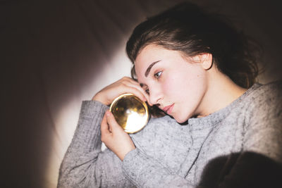 Thoughtful woman with crystal ball at home