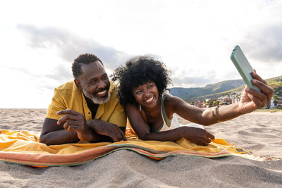 Portrait of young woman using mobile phone while sitting on beach