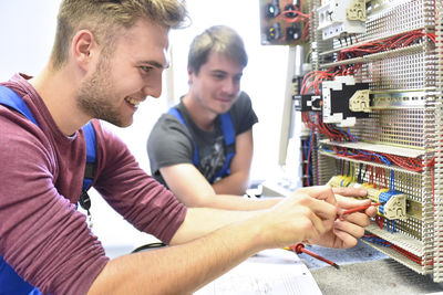 Two electrician students working at electrical panel