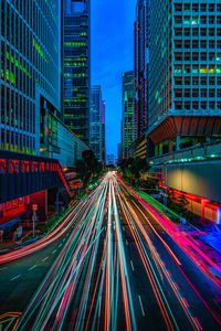 Light trails on road amidst buildings in city at night