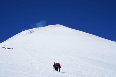 People on snowcapped mountain against clear sky