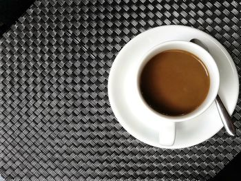 White coffee cup and espresso coffee on old wooden table near window with light shade at hotel.