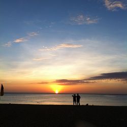 Silhouette people on beach against sky during sunset