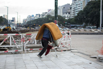 Disabled man carrying mattress on street