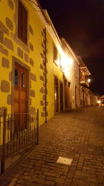 Empty alley amidst buildings in city at night