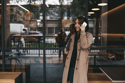 Young woman using mobile phone while standing at home