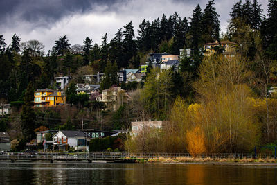 Buildings by lake against sky