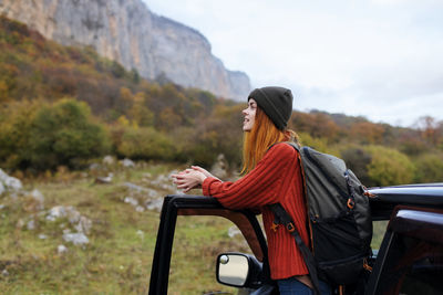 Woman looking away while sitting on mountain