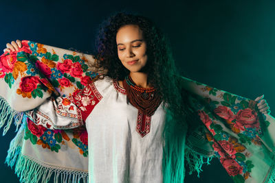 Portrait of young woman standing against black background