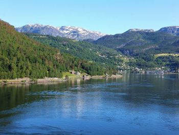 Scenic view of lake and mountains against clear blue sky