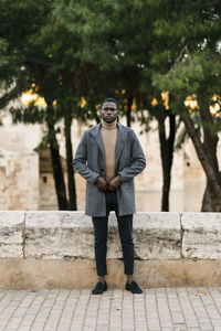 Fashionable man staring while standing on footpath