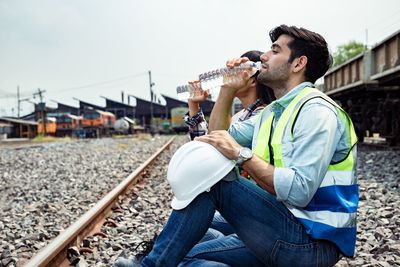 Side view of man sitting on railroad track