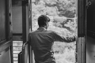 Rear view of man standing by train window