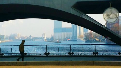 Man looking at cityscape seen through bridge