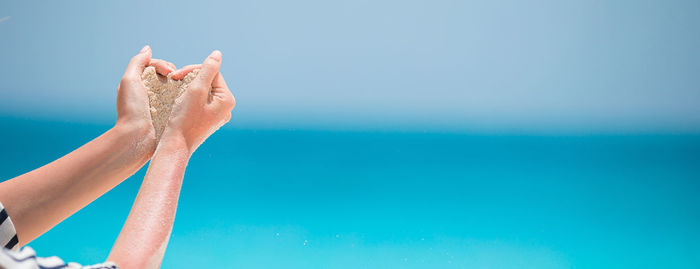 Low section of woman relaxing against blue background