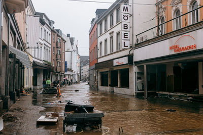 Wet street amidst buildings in city