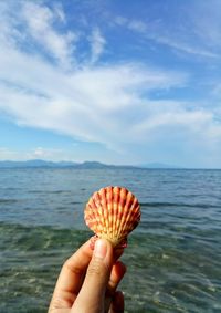 Close-up of hand holding ice cream against sea