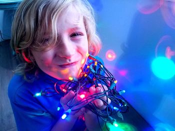 Close-up portrait of boy with illuminated string lights