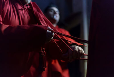 Midsection of man holding red while standing in dark