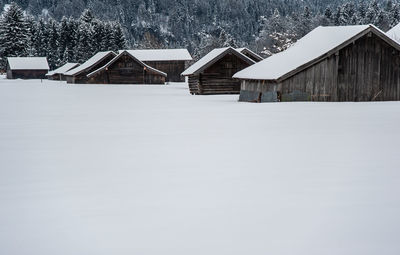 Houses on snow covered field against buildings