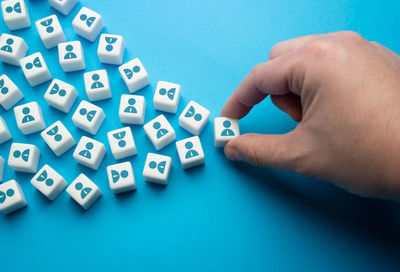 Close-up of hand holding key against blue background