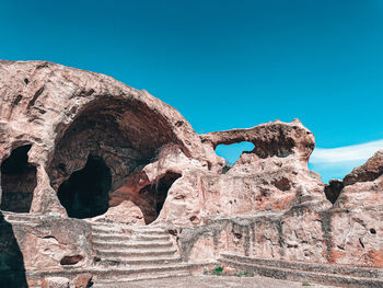 Low angle view of rock formations against clear blue sky