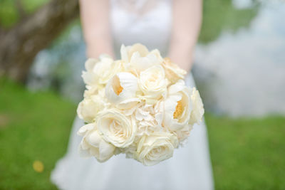 Midsection of bride with white rose bouquet