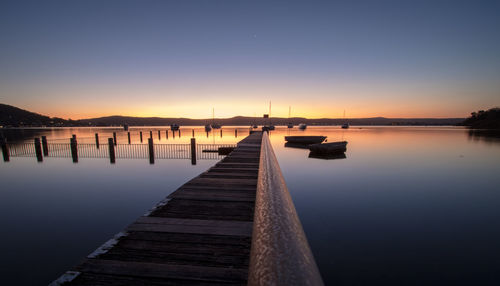 Pier over lake against clear sky during sunset
