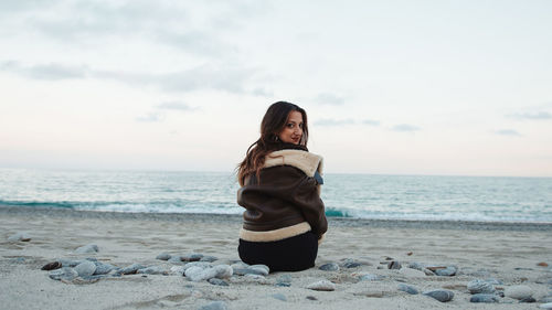 Side view of woman looking at sea against sky