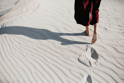Low section of woman walking on sand at desert