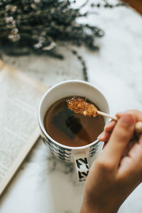 Cropped image of hand holding coffee cup on table