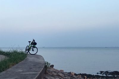 Man riding bicycle by sea against sky
