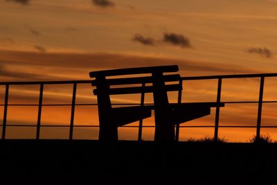 Silhouette built structure against orange sky