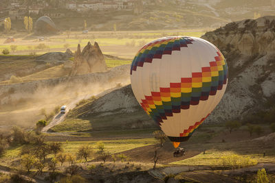 Multi colored hot air balloon flying over land