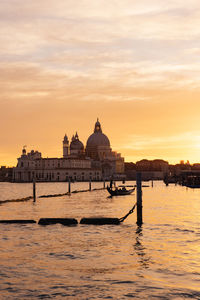 Dramatic sunset in venice, italy with silhouette of gondola and landmarks in the background. 