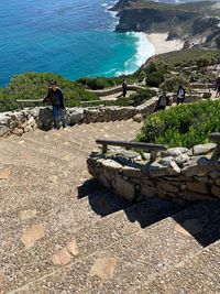 Rear view of man on rock by sea