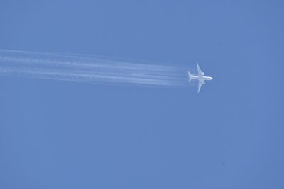 Low angle view of airplane flying against clear blue sky