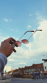 Person holding umbrella against sky in city