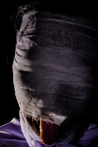 Close-up of man covering face against black background