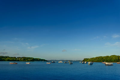 Boats sailing in sea against blue sky
