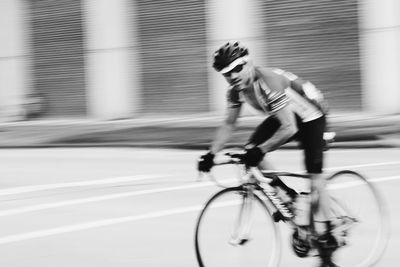 Blurred motion of man riding bicycle on road