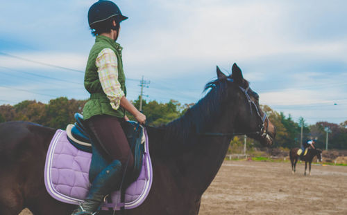 Jockey riding horse on track against sky