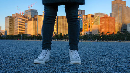 Low section of man standing by buildings against sky