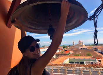 Smiling woman holding bell at church tower in town