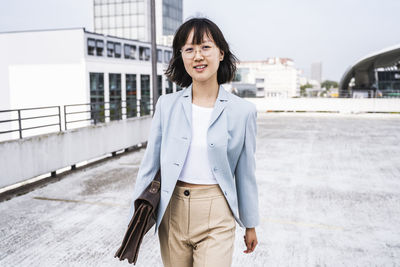 Businesswoman with briefcase walking on parking garage rooftop