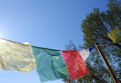 Low angle view of flags hanging against blue sky