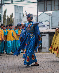 Full length of woman wearing blue traditional clothing dancing on city street